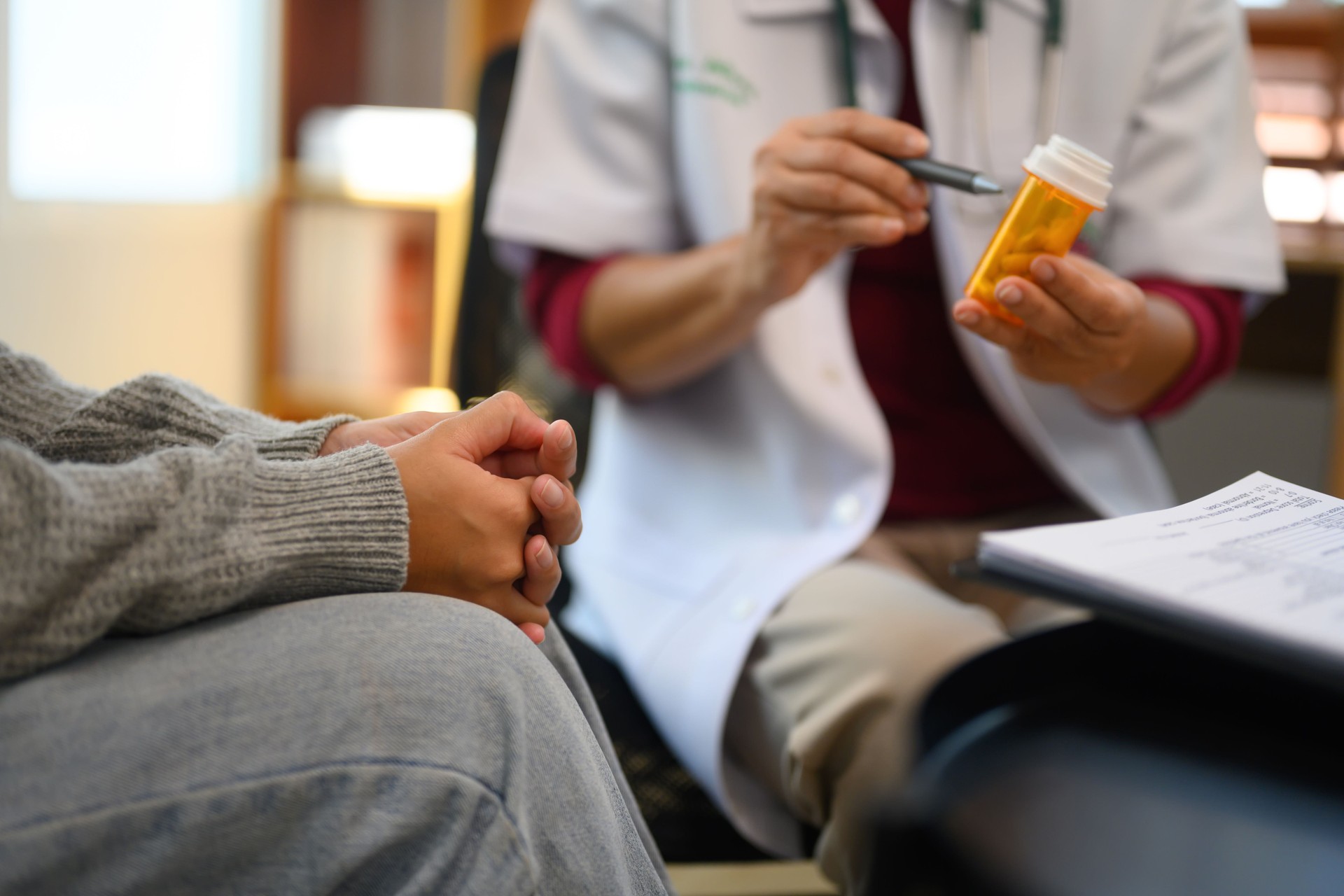 Doctor holding a bottle of prescription medication and explaining or discussing the treatment plan with patient
